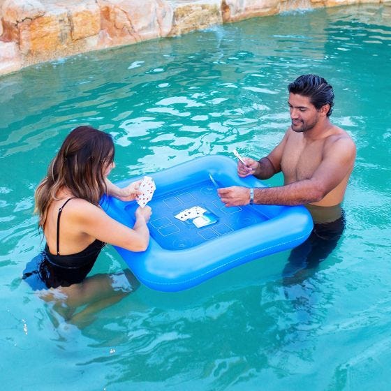 man and woman playing a card game in the pool